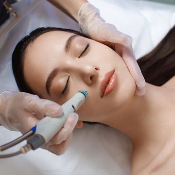 professional female cosmetologist doing hydrafacial procedure in cosmetology clinic