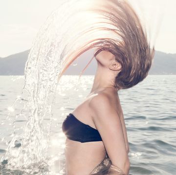 young woman in sea throwing head back